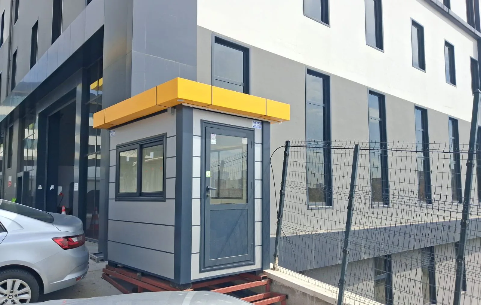 Grey composite cabin with a yellow roof fascia, sitting on steel skids beside a newly built food production building.