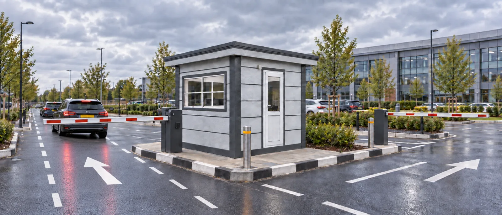 Car park attendant cabin between barrier arms on a kerbed island in a business park car park