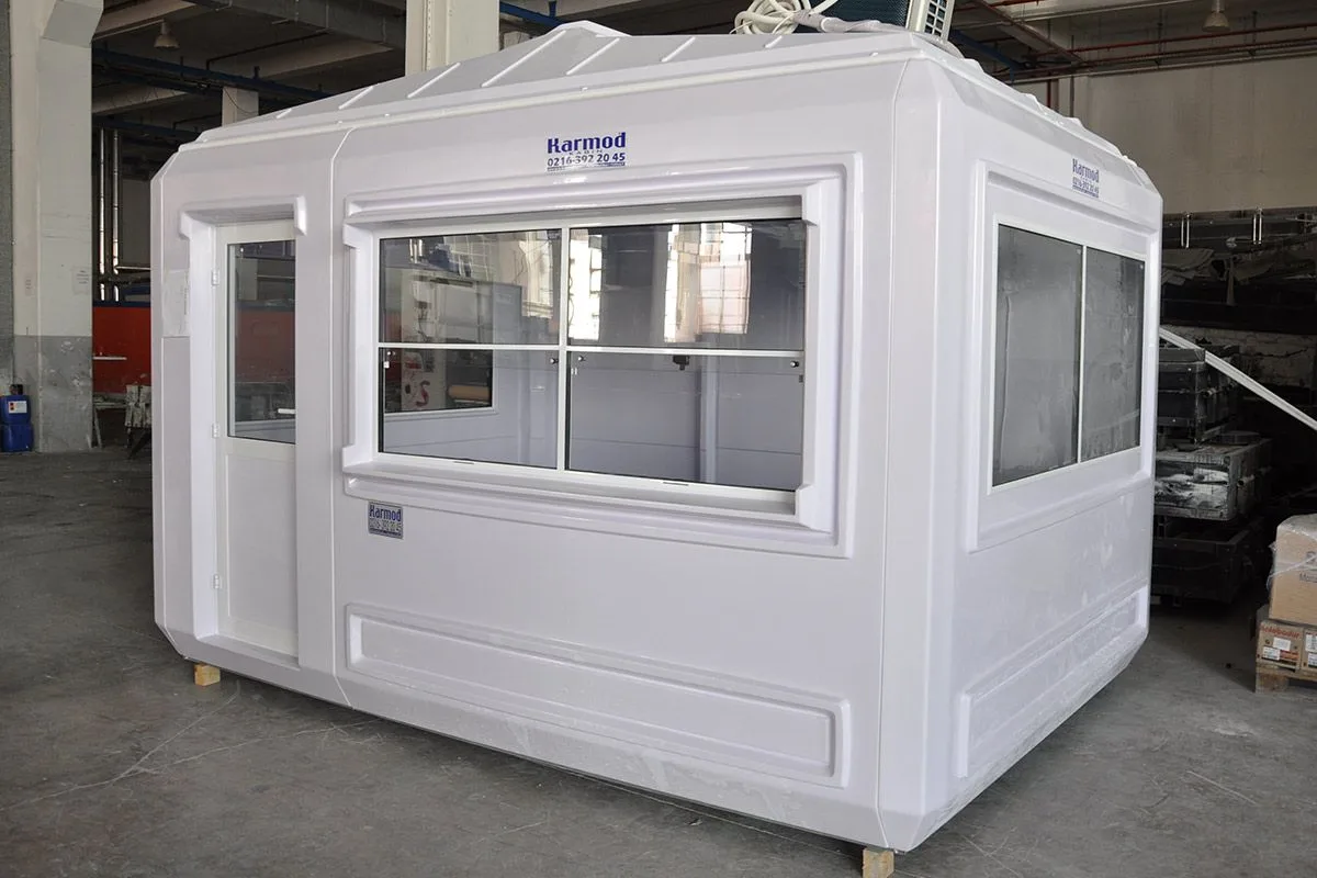 White GRP kiosk cabin with a full-width sliding service window, photographed inside the production facility before dispatch.