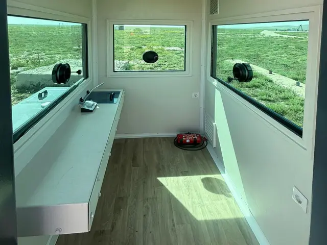Inside an armoured cabin: a full-length worktop beneath ballistic glazing, for long shifts