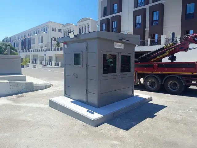 Armoured gatehouse set down on its concrete plinth at a financial centre, with the lorry-mounted crane behind