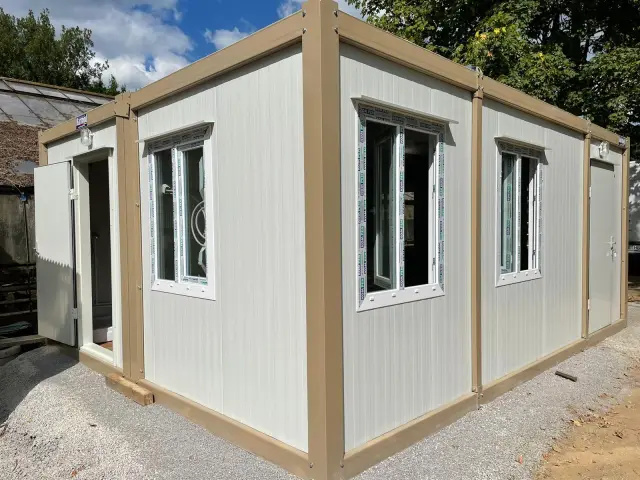 Newly delivered container unit with a fitted shower room behind the open door, protective film still on the frames