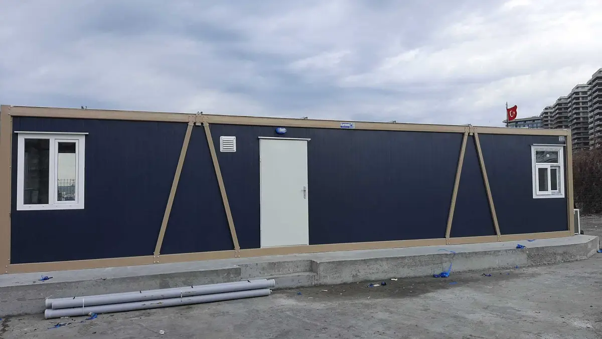 Navy blue container site office on a poured concrete plinth at a city-centre development