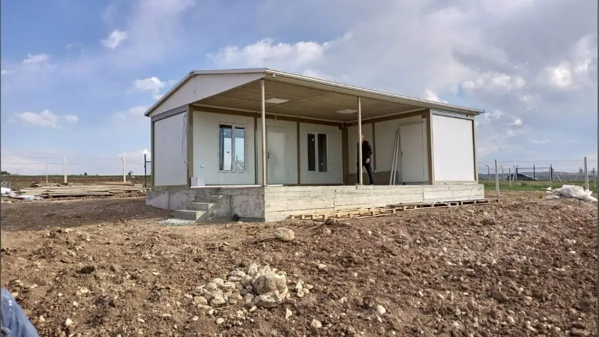 Container house part-way through installation on a levelled plot, with its canopy and terrace already in place