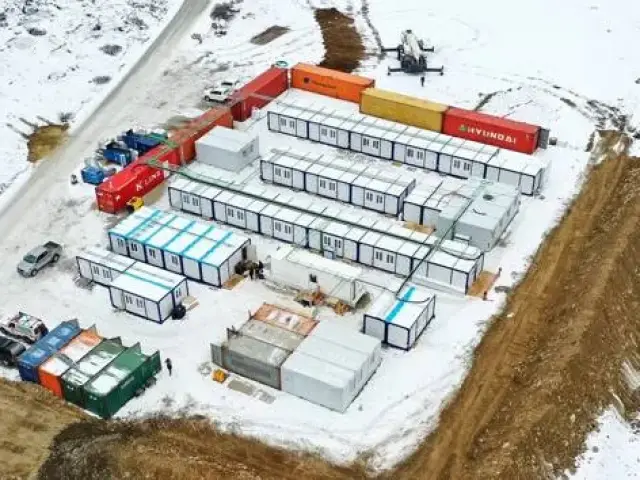 Container site camp in snow seen from above, with office and welfare units set around a central yard