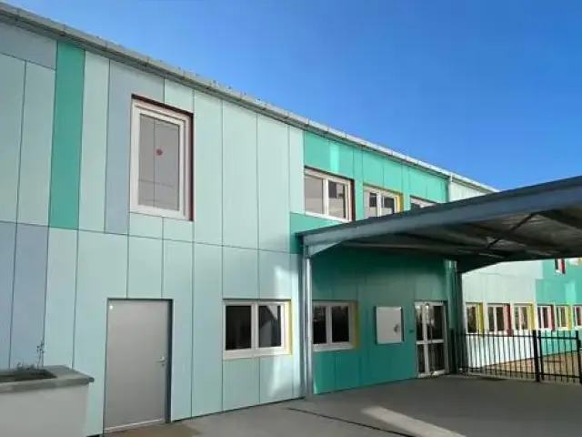 Two-storey modular building with mint and green cladding panels and a covered walkway at the entrance