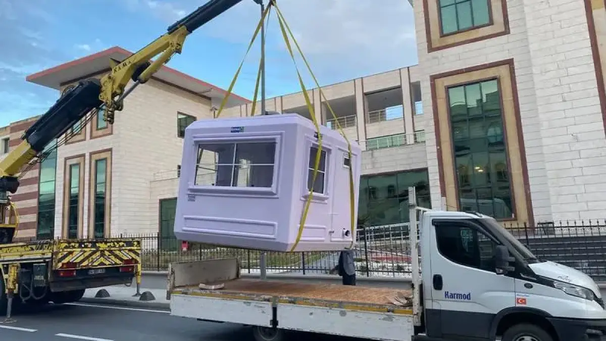 Lilac GRP kiosk lifted on straps off a delivery lorry by a separate truck-mounted crane