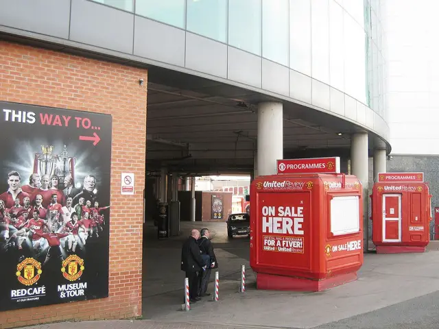 Moulded GRP kiosks in red United Review colours selling programmes outside the East Stand at Old Trafford