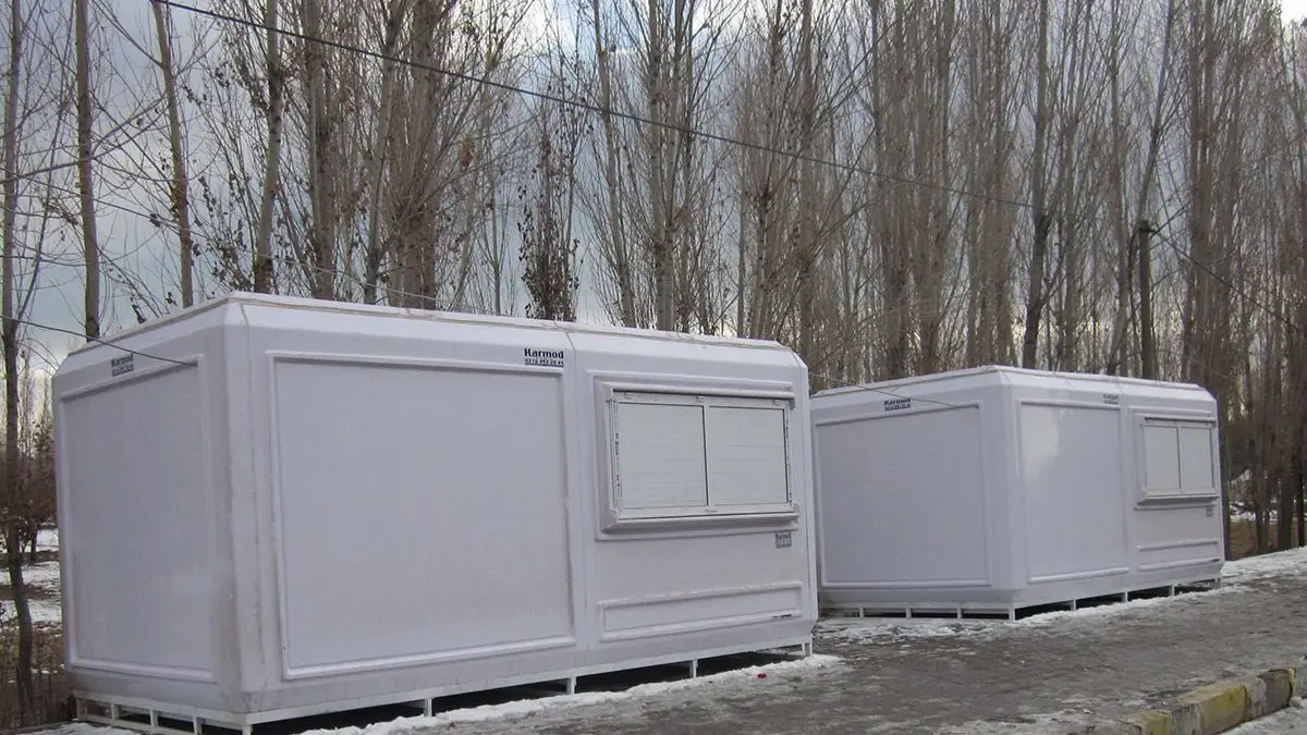 Pair of GRP cabins standing beside a road in deep winter snow and freezing conditions