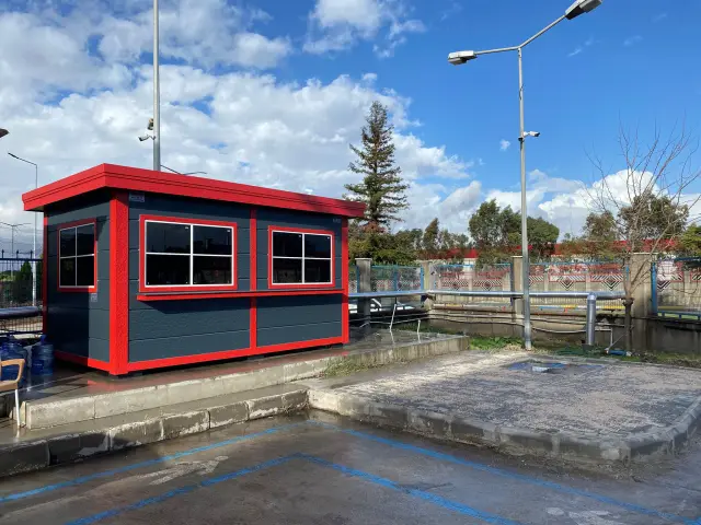 Grey MetroCity site office with red trim at Mosb Enerji, on a raised concrete plinth beside a car park