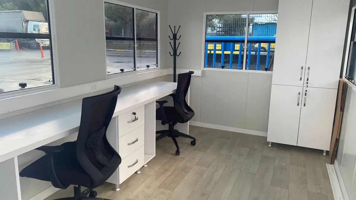 Inside the Mosb Enerji MetroCity office: two desk chairs at one long worktop, a tall cupboard and windows on two walls