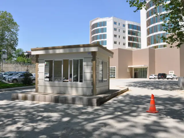 Stone-effect MetroCity security booth on a low plinth in a hospital car park, with the hospital behind