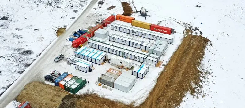 Aerial view of a container site camp in snow with rows of units and storage containers
