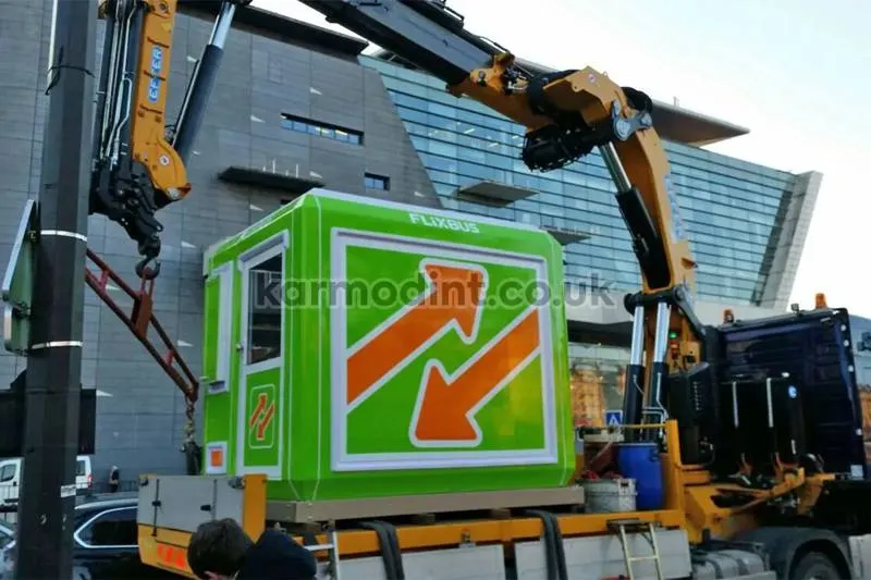 FlixBus GRP kiosk lifted off a lorry by a truck-mounted crane