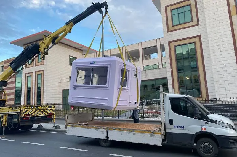 Lilac GRP kiosk lifted on straps by a truck-mounted crane